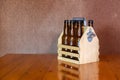 Wooden carrying case for six beer bottles with a metal bottle opener on a side.