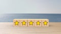 Wooden cartoon cube five yellow star review on blur sea with the sky background. Service rating, satisfaction concept. reviews and