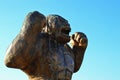 Wooden carved raging gorilla monkey statue, light blue clear skies in background.