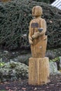 Wooden carving sculpture of a life-sized man figure Mr Leefe holding three iron roses, by Andy Rogers.