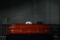 Casket with white lilies and burning candles in funeral home