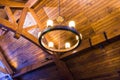 Wooden ceiling and rustic vintage chandelier with electric bulbs. Classic luxury home architecture