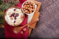 Wooden and ceramic bowls of yogurt and hazelnuts on red napkin on tray on wooden table. Royalty Free Stock Photo