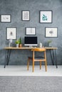 Wooden chair at desk with desktop computer against grey wall wit Royalty Free Stock Photo