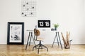 Wooden chair at desk with desktop computer in white home office interior with poster. Real photo Royalty Free Stock Photo