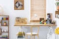 Wooden chair at desk with lamp and colorful yarns in home office interior with poster. Real photo Royalty Free Stock Photo