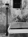 Wooden chair lonely resting with street antique lamp in front of old concrete wall, in black and white tone. Royalty Free Stock Photo