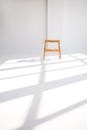 Wooden chair in a white room with shadows from the windows