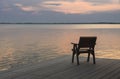 Wooden chair on a wood pier overlooking calm lake at sunset skyline Royalty Free Stock Photo