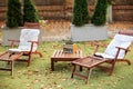 Wooden chairs in autumn garden. Vintage radio on table. Two deckchairs on green summer lawn on picnic. Lounge sunbed. Wooden gard