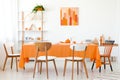 Wooden chairs at orange table in white dining room