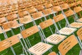 Wooden chairs outside in the park in the rain. Empty auditorium, grass and water drops Royalty Free Stock Photo