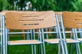 Wooden chairs stand outside in the park in the rain. Empty auditorium, green grass, waterdrops, closeup Royalty Free Stock Photo