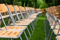 Wooden chairs stand outside in the park in the rain. Empty auditorium, green grass, waterdrops, closeup Royalty Free Stock Photo