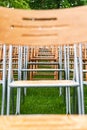 Wooden chairs stand outside in the park in the rain. Empty auditorium, green grass, waterdrops, closeup Royalty Free Stock Photo