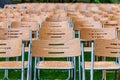 Wooden chairs stand outside in the park in the rain. Empty auditorium, green grass, waterdrops, closeup Royalty Free Stock Photo