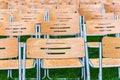 Wooden chairs stand outside in the park in the rain. Empty auditorium, green grass, waterdrops, closeup Royalty Free Stock Photo