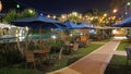 Wooden chairs with statues beside the pool and beach with sparkling lights at night Royalty Free Stock Photo