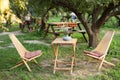 Wooden chairs and table table in summer orchard. Wooden outdoor furniture set for Picnic in garden. Cozy Interior Courtyard with t Royalty Free Stock Photo