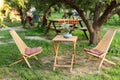 Wooden chairs and table table in summer orchard. Wooden outdoor furniture set for Picnic in garden. Cozy Interior Courtyard with t Royalty Free Stock Photo