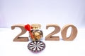 2020 wooden character and dart board with glass piggy bank and gold coins, set new business goals with New Year 2020