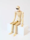 Wooden character sitting in deep thought