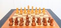 Wooden chess board with pieces on it. Leather frame, close up view, details, white background. Royalty Free Stock Photo