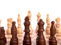 Wooden chess pieces in a duel on a chessboard. King, lady and shooter. Out of focus team of enemies. Isolated on white background Royalty Free Stock Photo