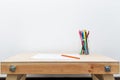 Wooden child drawing table with color pencils by the white wall Royalty Free Stock Photo