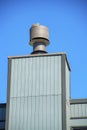 Wooden chimney with gray metal chimney vents and clear blue sky background with gray roof tiles in the late afternoon Royalty Free Stock Photo