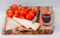 Wooden chopping board with cherry tomatoes, cheese and a glass of red wine Royalty Free Stock Photo