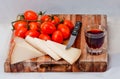 Wooden chopping board with cherry tomatoes, cheese and a glass of red wine Royalty Free Stock Photo