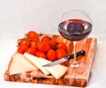 Wooden chopping board with cherry tomatoes, cheese and a glass of red wine Royalty Free Stock Photo