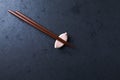 Wooden chopsticks and chopstick rest on dark stone background. Top view. Royalty Free Stock Photo