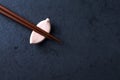 Wooden chopsticks and chopstick rest on dark stone background. Top view. Royalty Free Stock Photo