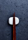 Wooden chopsticks and chopstick rest on dark stone background. Royalty Free Stock Photo