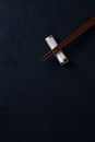 Wooden chopsticks and chopstick rest on dark stone background. Royalty Free Stock Photo