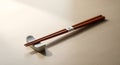 Wooden chopsticks resting on a white ceramic chopstick rest on a light wood grain surface. Royalty Free Stock Photo