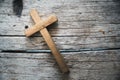 A wooden Christian cross crucifix on a grunge board background. Wooden Christian cross on grey table against blurred lights, space