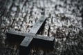 A wooden Christian cross crucifix on a grunge board background. Wooden Christian cross on grey table against blurred lights, space Royalty Free Stock Photo