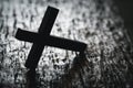 A wooden Christian cross crucifix on a grunge board background. Wooden Christian cross on grey table against blurred lights, space