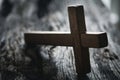 A wooden Christian cross crucifix on a grunge board background. Wooden Christian cross on grey table against blurred lights, space