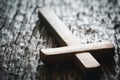 A wooden Christian cross crucifix on a grunge board background. Wooden Christian cross on grey table against blurred lights, space