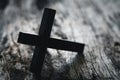 A wooden Christian cross crucifix on a grunge board background. Wooden Christian cross on grey table against blurred lights, space