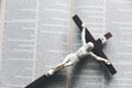 Wooden Christian cross crucifix on open holy bible background. Wooden Christian cross on grey table against blurred lights, space Royalty Free Stock Photo