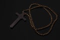 Wooden christian cross necklace on black background