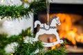 Wooden Christmas decoration in the shape of white horse with the flame of fireplace in background