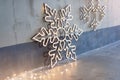 Wooden christmas decoration for the walls. Glowing snowflakes with garland lights on gray concrete background. Christmas backgroun