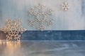 Wooden christmas decoration for the walls. Glowing snowflakes with garland lights on gray concrete background. Christmas Royalty Free Stock Photo