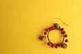 Wooden Christmas ornament hanger with small pine cones and red berries on a yellow background Royalty Free Stock Photo